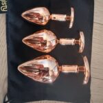 Trzy metalowe korki Elva w kolorze rose gold na czarnym woreczku gisty