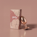 Elva L — metalowy korek analny w kolorze rose gold, widok z boku, obok pudełko gisty